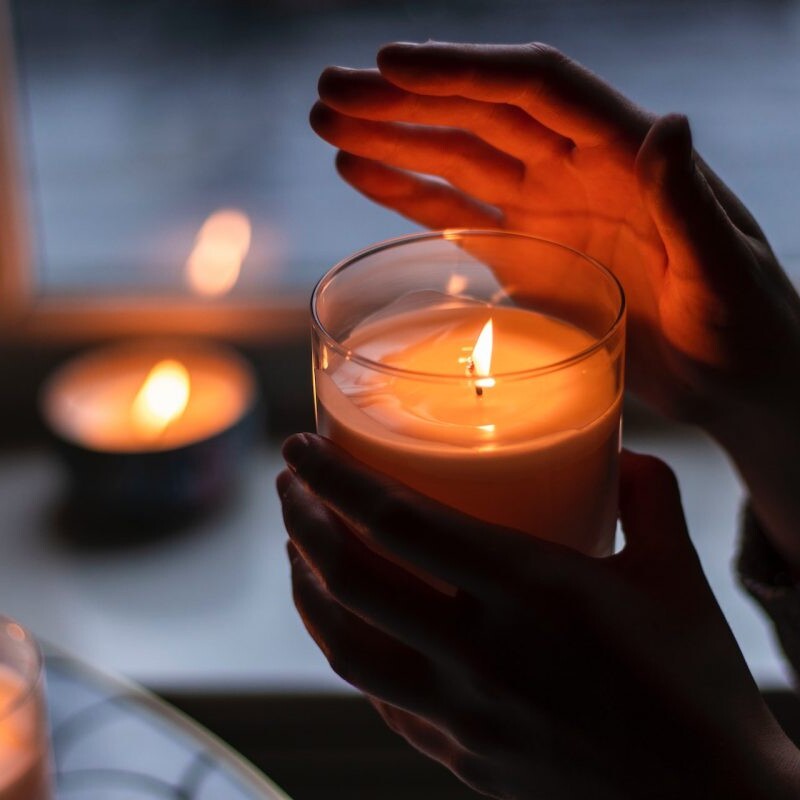 Person holding candle with one hand over the light