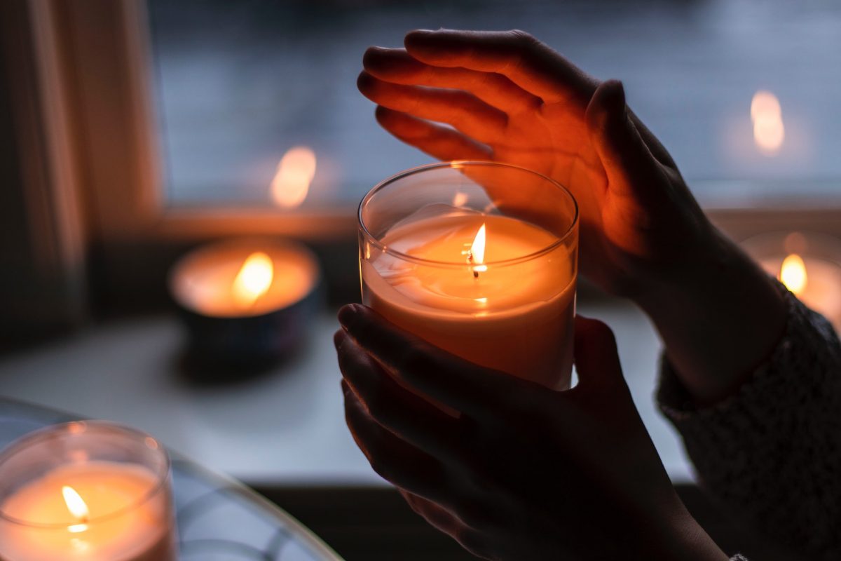Person holding candle with one hand over the light